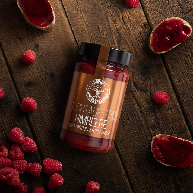 ein Glas Marmelade neben Himbeeren